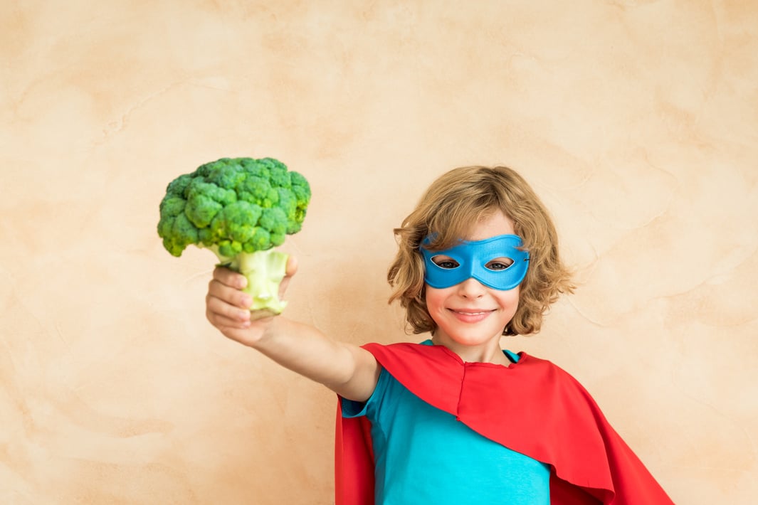 Pediatric GI. Superhero kid holding broccoli. 